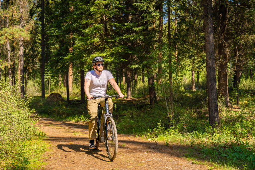 Man riding bike through a path in forest.